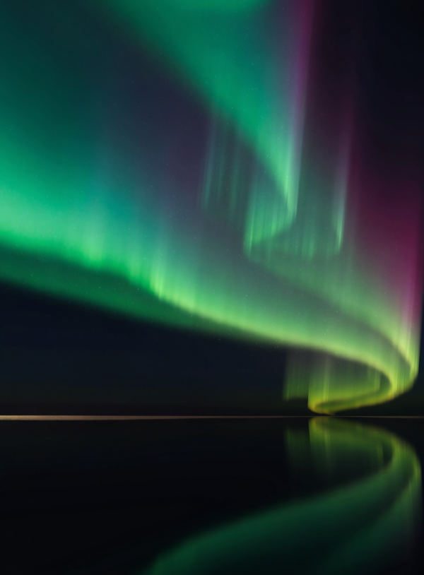 Flat digital painting of a green, magenta and blue aurora over a low horizon of still water, with a thin band of pale gold at the waterline.