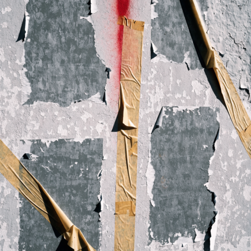 A weathered, sun-bleached plaster wall showing the pale rectangle left by a removed poster, grey tape shadows at the corners, and a faded spray fade running across the middle. A weathered, sun-bleached plaster wall showing the pale rectangle left by a removed poster, grey tape shadows at the corners, and a faded spray fade running across the middle.