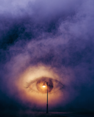 A single warm lamp glowing through violet and indigo fog, its halo shaped like a partly open eye.