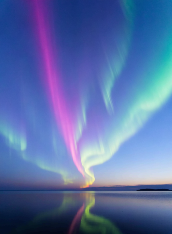 jPDRGjzykgN1GSSZdQwzf_6QIGu4WH.webp Flowing green, magenta and cold blue aurora bands filling a large sky above a flat horizon of still water with a thin band of pale gold at the waterline.