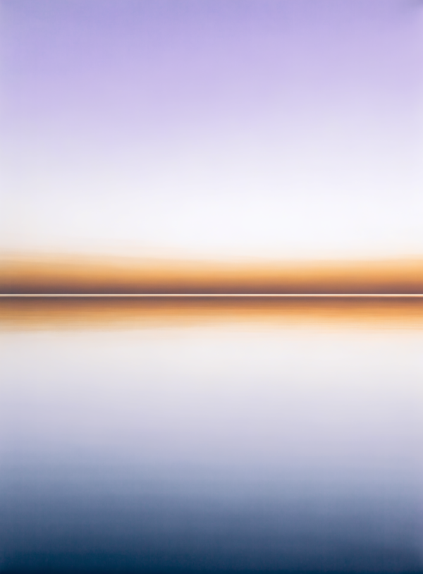 A minimalist Nordic horizon: a wide band of pale gold sky above still cold blue water, with no objects or details in the frame. A minimalist Nordic horizon: a wide band of pale gold sky above still cold blue water, with no objects or details in the frame.