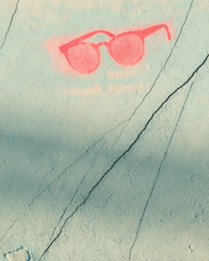 Flat cracked mint and cream plaster wall with a painted-over patch and a small coral pink stencilled sunglasses shape near one edge.